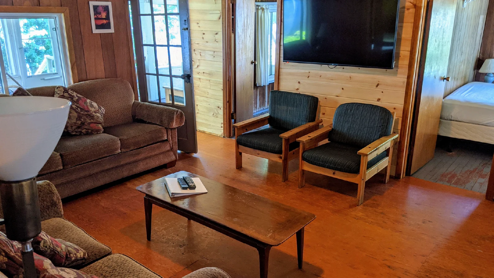 Pigeon Lake Resort Cottage three living room with sofa, chairs, coffee table, and wall-mounted television.
